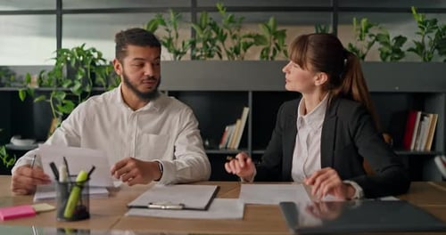Two Colleagues Discussing Business at Office Desk