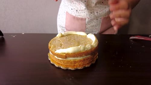 Lateinamerikanische Frau mit Schürze, bereitet das Kochen vor, backt einen Kuchen, fügt Butter hinzu, vermischt mit einem Spritzbeutel