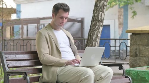 Man Working on Laptop on Park Bench