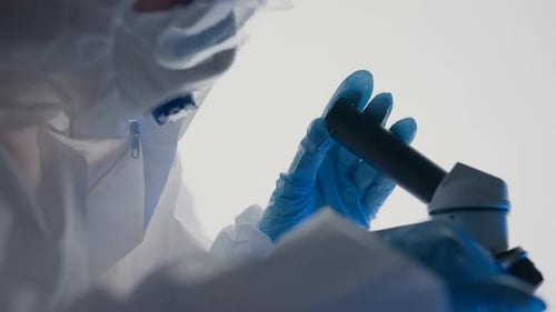 Scientist in Protective Suit Using Microscope