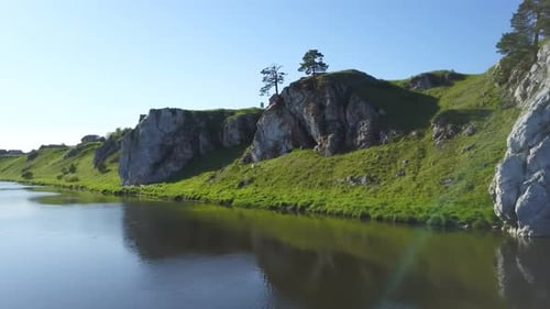 A Serene River Landscape Featuring Lush Green Hills Surrounded By Rocky Outcrops Nearby Stock Clip