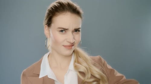 Upset businesswoman shows thumbs down gesture in studio portrait on gray background