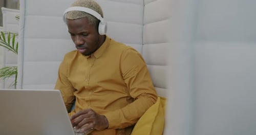 Young Adult Working on Laptop with Headphones
