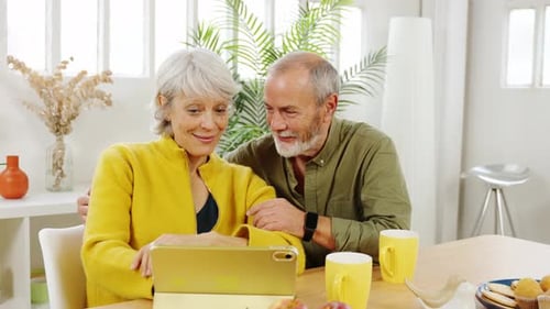 Senior Couple Using Tablet at Kitchen Table