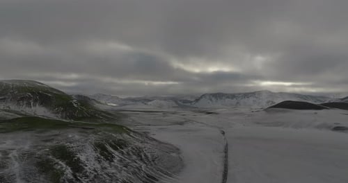 aerial view of f-road in highlands in snow with mountains on background with rays of sun
