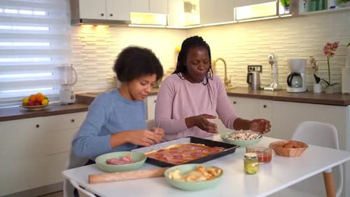 Two Females Preparing Pizza Together in Modern Kitchen