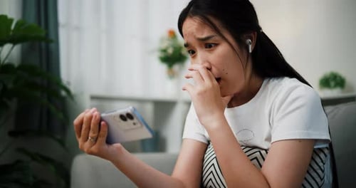 Worried Woman Looks at Mobile Phone