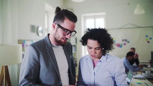 Two Young Businesspeople in a Modern Office, Talking