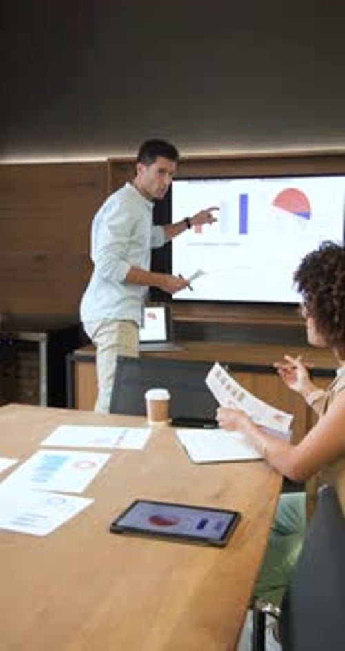 Receiving printed reports, Diverse coworkers discussing data and pointing at graphs in boardroom