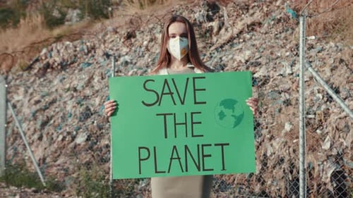 Woman Holding Save the Planet Sign at Landfill