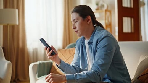 Excited man celebrates success using smartphone indoors