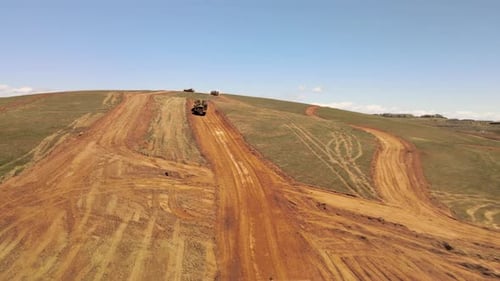 Aerial view dump trucks, bulldozers and crawler loaders doing earth work on a construction project