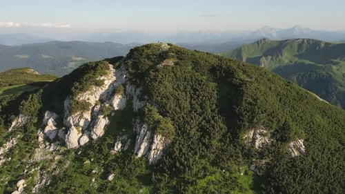 The drone flies over the top of the mountain on which the person is standing. Aerial view.