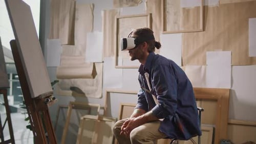 Male Artist Using VR Headset to Paint in His Bright Studio Surrounded By Artwork