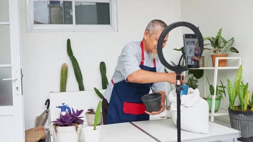 Gardener saluda a los espectadores durante la transmisión en vivo mientras da un tutorial sobre cómo llenar macetas con tierra