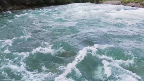 Aerial view of a powerful river flowing through a forest and creating white water rapids
