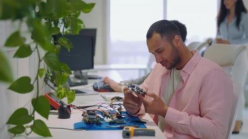 Man Inspecting Circuit Board at Tech Workplace