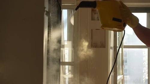 Hand Using Portable Steamer to Clean Vent