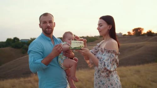 Happy Family with Baby Celebrate First Year Eat Cake in Field at Sunset Autumn and Lifestyle