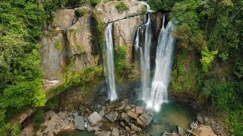 Majestic waterfall cascading down rocky cliffs surrounded by topical forest