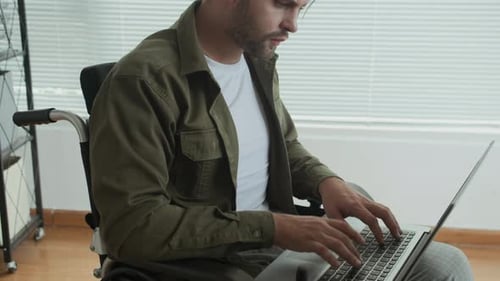 Employee with Disability Working on Laptop at Modern Office Space