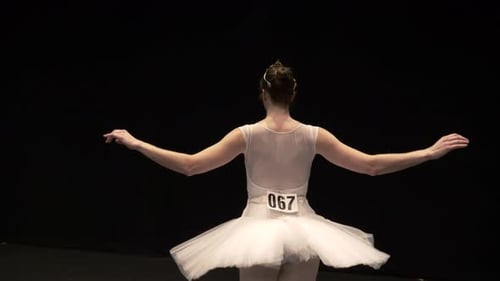 Graceful Ballerina Practicing on Dark Stage Before Performance