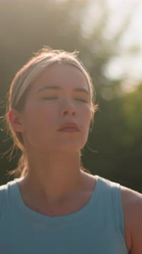 Jeune femme marchant pensivement sous la lumière du soleil avec fond de verdure