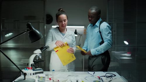Forensic Scientist Reviewing Evidence with Detective in Crime Laboratory