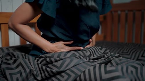 Woman lies in bed and feels pain and inflammation causing the uterine muscles to contract, causing