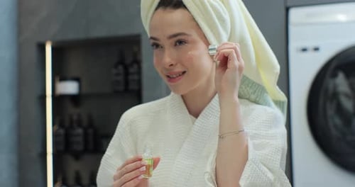 Woman Applies Serum to Face in Bathroom