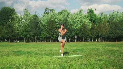Schönes Sportmädchen in streckt sich auf einer Sportmatte in einem Stadtpark. Yoga in einem sonnigen Ich