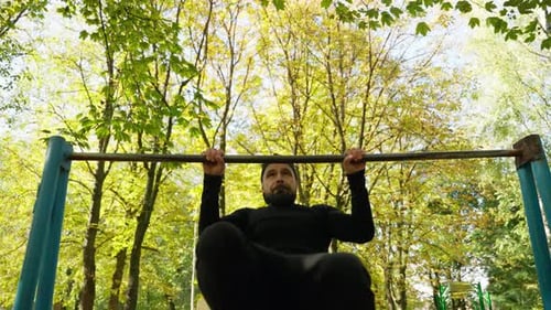 An Athlete Pulls Up on a Horizontal Bar on a Sports Field