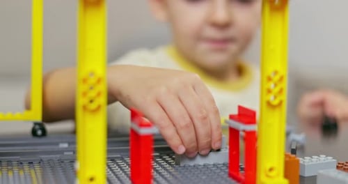 Child Boy Playing and Building with Colorful Plastic Bricks at the Table