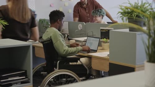 Jeune homme noir handicapé travaillant sur un ordinateur portable dans un espace de coworking