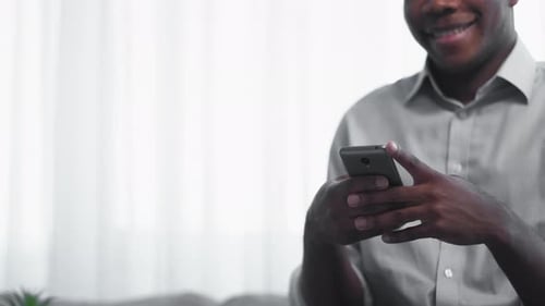 Smiling Man Uses Mobile Phone Indoors