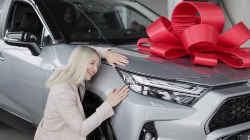 Saleswoman Leaning on New Car with Red Bow in Dealership