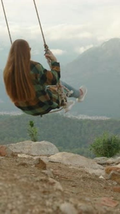 Vertical video. Homemade swings at the mountain summit, suspended over the abyss and tied to a tree