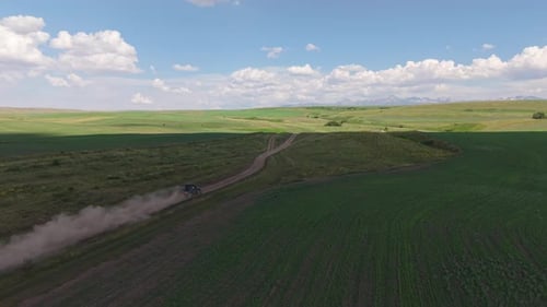 Black Off Road Vehicle Crossing Green Fields Leaving Dust Trail