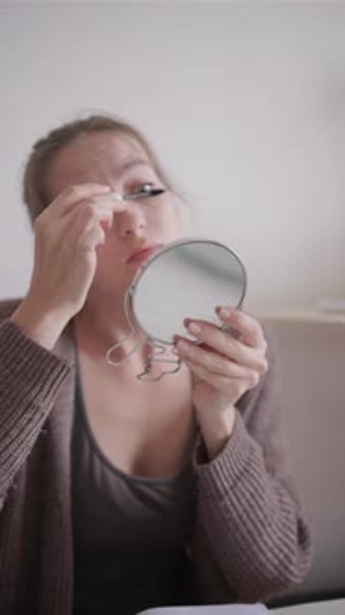 Frau schminkt sich, trägt schwarze Wimperntusche in Nahaufnahme auf, Schönheit, Mädchen, bereitet sich auf die Arbeit vor und bewundert attraktiv
