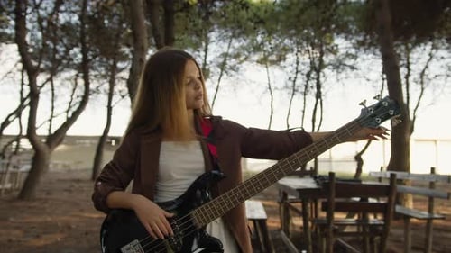 Girl Adjust Handles To Tune Bass Musical Instrument In The Park