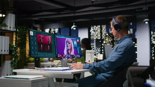Man Works on Dual Computer Monitors in Office