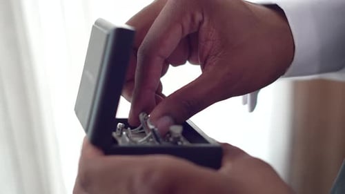 Man Holds Silver Cufflinks in Black Box