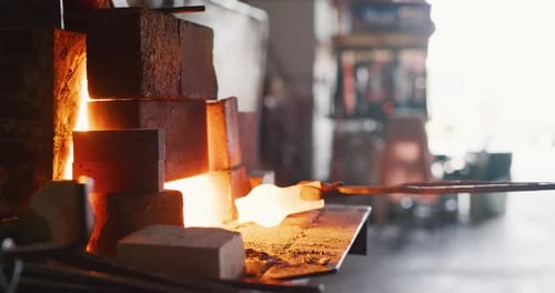 Professional metalsmith forging red hot metal in dark blacksmith workshop