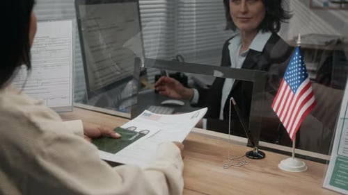 Female USA Visa Applicant Handing Documents to American Embassy Official
