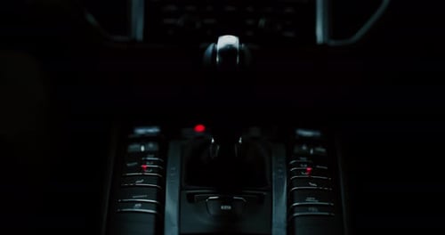 Close-up de um empresário movendo manualmente a transmissão de um carro moderno de luxo anônimo de prestígio.
S