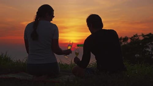 Silhouette of Couple Sitting on Hill Drinking Champagne Together while Watching Sunset, Romantic Mom