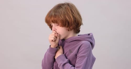 Little boy coughing on light background. Cold symptom