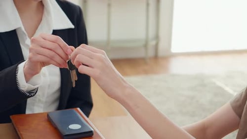 Closeup hands real estate agent giving house key with couple after success property purchase home.
