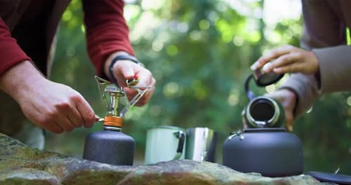 Adults Making Tea Outdoors Using Portable Gas Stove