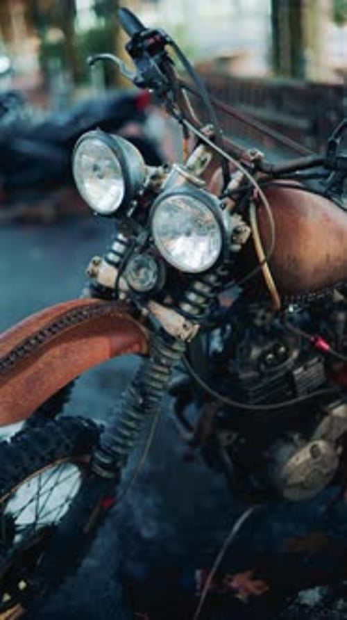 Close up of a vintage rusty motorcycle parked on a city street